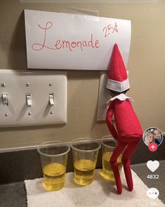 an elf is standing in front of three cups and a sign that says lemonade