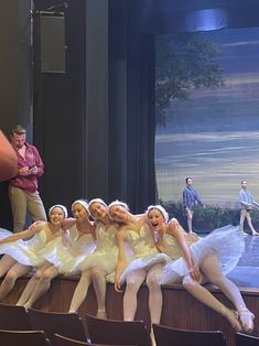 a group of young ballerinas sitting on top of a stage