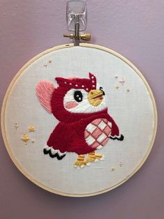 an embroidered owl in a red dress with stars on it's head is hanging from a hoop