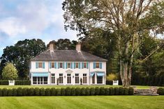 a large white house sitting on top of a lush green field