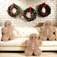 two decorative gingerbreads sitting on a couch in front of christmas wreaths and wreath decorations