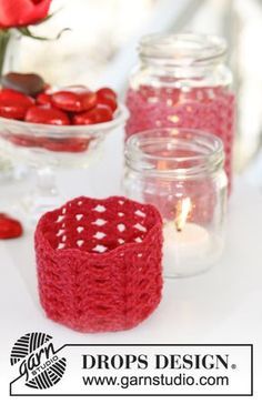 red crocheted candle holders on a table with flowers and candles in the background