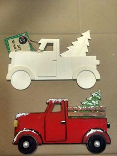 a red truck with a christmas tree on the back is sitting in front of a cardboard box