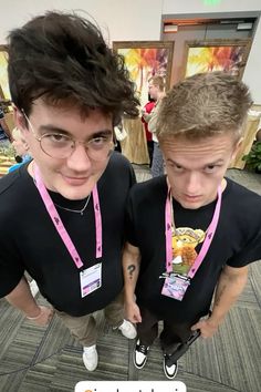 two young men standing next to each other wearing black t - shirts and pink ties