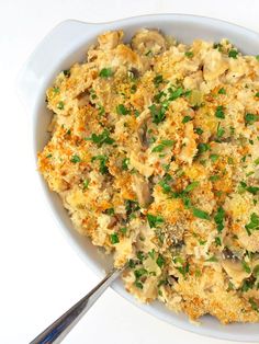 a white bowl filled with mashed potatoes and green onions on top of a table