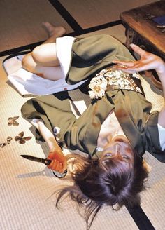 a woman laying on the floor with her hands in her hair and holding a knife