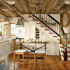 a kitchen with wooden floors and white walls, along with stairs leading up to the second floor