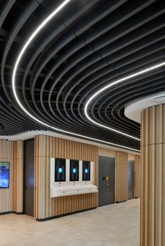 an empty room with three urinals in the center and two television screens on the wall