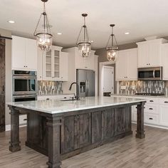 a large kitchen with white cabinets and an island in the middle of the flooring