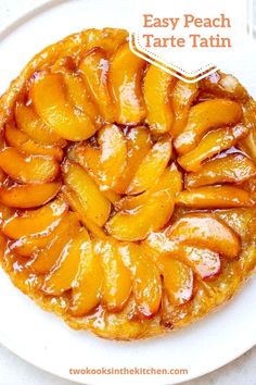 a white plate topped with a pastry covered in sliced peaches