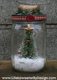 a glass jar filled with snow and a small christmas tree