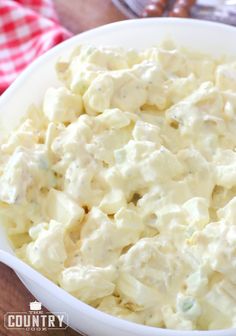 a white bowl filled with potato salad on top of a table