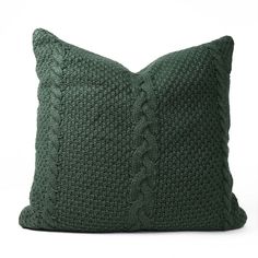 a green knitted pillow on a white background