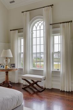 a bedroom with two windows and a bench in front of the window, next to a bed