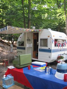 an rv is parked in the woods next to a picnic table with food on it