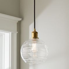 a glass light fixture hanging from a ceiling in a room with white walls and windows