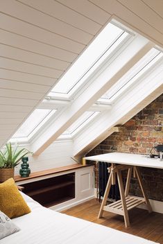 an attic bedroom with exposed brick wall and skylights