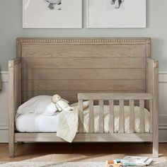 a baby crib with two pictures on the wall above it