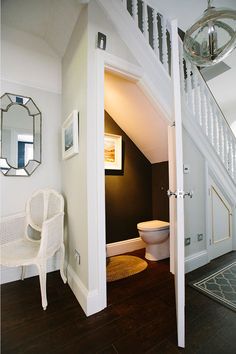 an open door leading to a bathroom with a toilet next to a sink and mirror