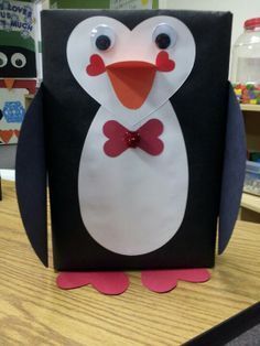 a penguin with a red bow tie on it's head sitting on a table