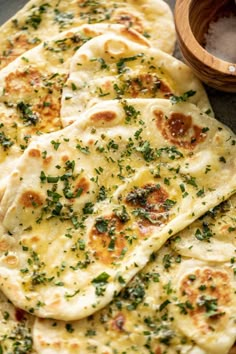 several flat breads with herbs on them next to a wooden bowl