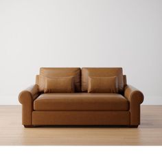 a brown leather couch sitting on top of a hard wood floor next to a white wall