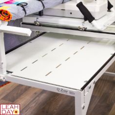 a sewing machine sitting on top of a wooden floor next to a table with an ironing board