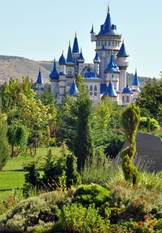 the castle is surrounded by lush green trees and shrubs, with blue domes on its roof