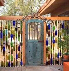 a wooden gate with glass bottles hanging from it's sides and a green door