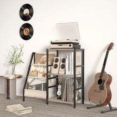 there is a record player and guitar on the floor next to a shelf with records