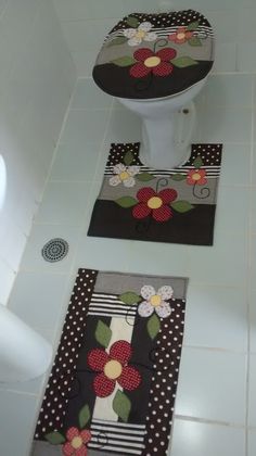 two toilet mats with flowers on them in a white tiled bath room next to a toilet