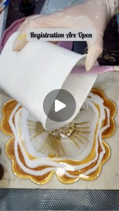 a person pouring liquid onto a plate with gold and white designs on it that reads, registration are open