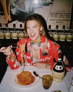 a woman sitting at a table eating spaghetti