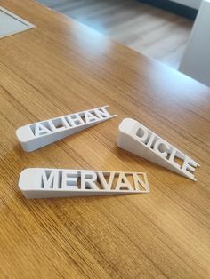 three plastic name tags sitting on top of a wooden table