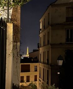 the eiffel tower is lit up in the distance from some buildings at night