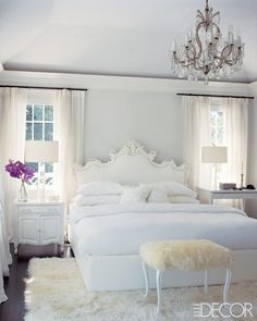 a white bed sitting in a bedroom next to a window