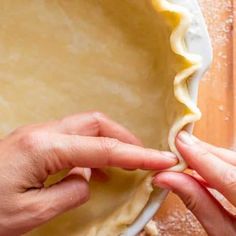 two hands are placing dough into a pie crust