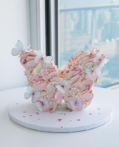 there is a sculpture made out of pink and white butterflies on top of a table