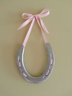 a pink ribbon tied to a metal horseshoe with the word atelia romana's post on it