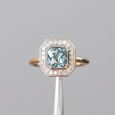 a fancy ring with an aqua blue diamond surrounded by white and yellow gold diamonds in the center