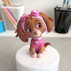 a small toy dog sitting on top of a cake