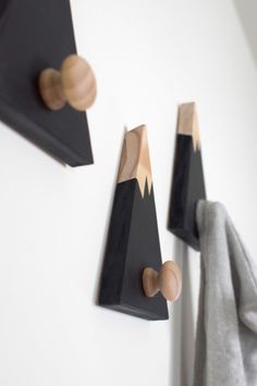 three wooden hooks mounted to the side of a white wall next to a gray towel