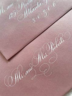 two pink envelopes with white calligraphy on them