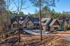 a large home in the woods with lots of trees and dirt on the side of it