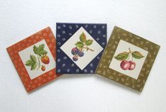 four small square coasters with fruit designs on them, all in different colors and patterns