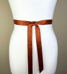 Extra Narrow Burnt Orange Sash  Dark Orange Satin Sash  Skinny Sash Belt  Thin Sash Belt  Skinny Orange Belt  Satin Orange Sash  Elevate your style with this extra narrow Satin Swank® waist sash. Depending on your waist size and the length you choose, you can wrap this sash around your waist once or twice. You decide whether to tie the sash in a bow or a simple knot with long-hanging tails. Tie in front, in back, or on the side. A double layer of silky satin fabric in burnt orange, this sash is constructed in one long piece. Ends are finished on the angle and seams are hidden within the fold lines. SIZING/COLOR/PRINT INFO: The mannequin pictured is wearing the 60 inch sash length and has a 28 inch waist. Sizes available: 1" wide x 60" long (point to point) 1" wide x 75" long (point to poin Orange Belt, Orange Chiffon, Waist Sash, Orange Satin, Satin Sash, Sash Belts, Sash Belt, Dark Orange, Suspender Belt