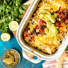 an enchilada casserole with avocado, tomatoes, and black beans