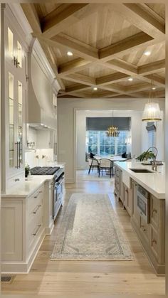 a large kitchen with white cabinets and wood ceilinging, along with an area rug on the floor