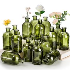 many green glass bottles with flowers in them