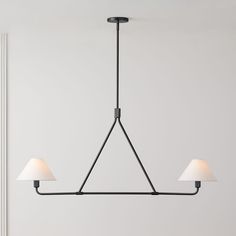 a black chandelier with three white lamps hanging from it's sides in a room